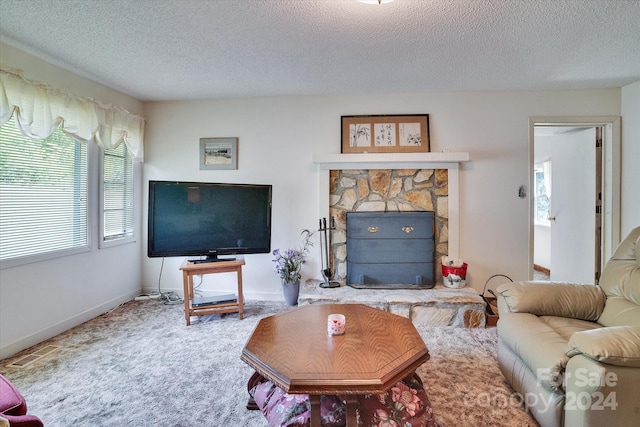 living room featuring a fireplace, carpet flooring, and a textured ceiling