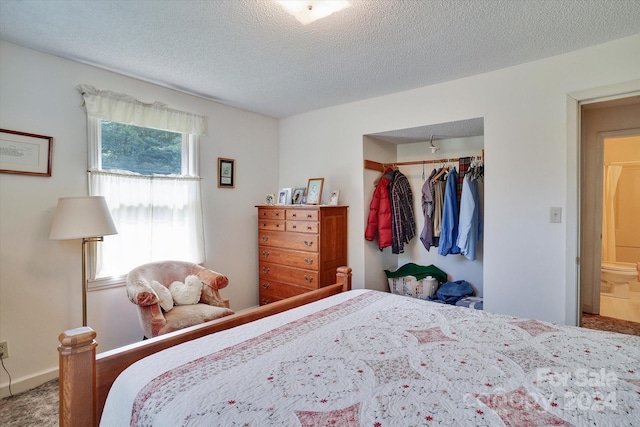 bedroom with multiple windows, a closet, a textured ceiling, and ensuite bath