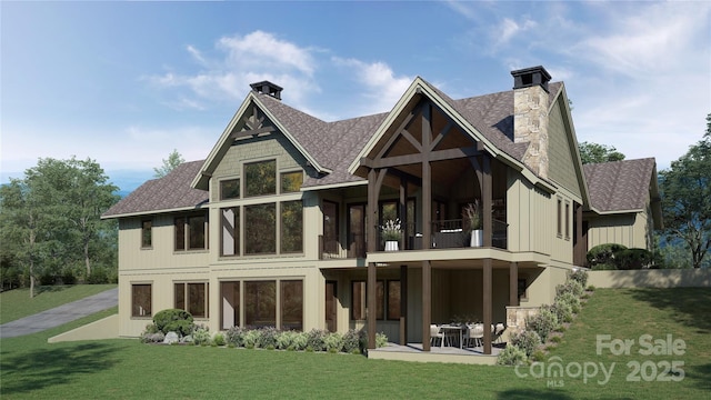 back of property with a lawn, a balcony, a chimney, roof with shingles, and a patio area