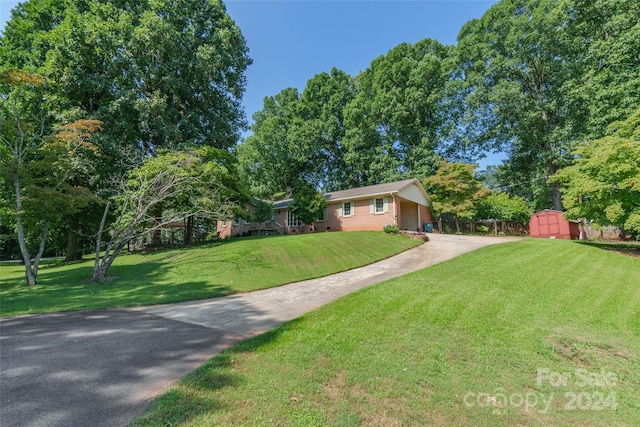 ranch-style house with a storage unit and a front lawn