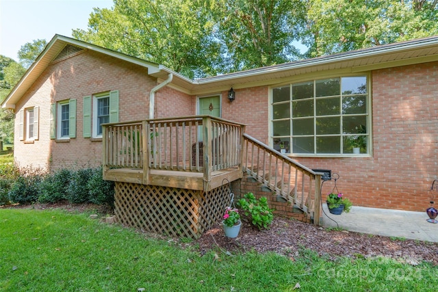 back of property with a deck and a lawn