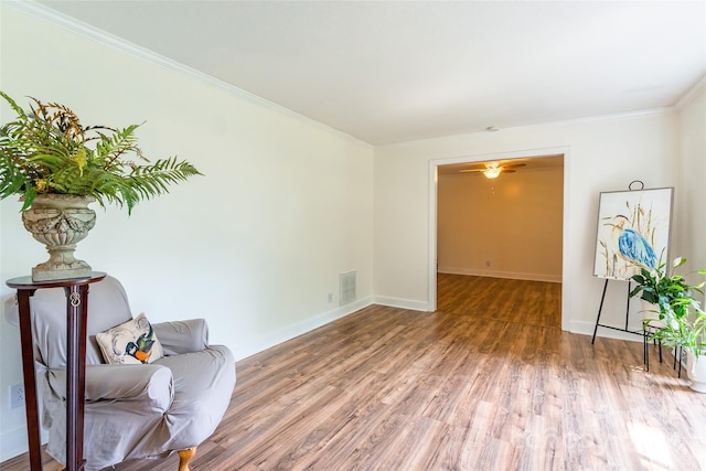 living area featuring hardwood / wood-style floors, ornamental molding, and ceiling fan