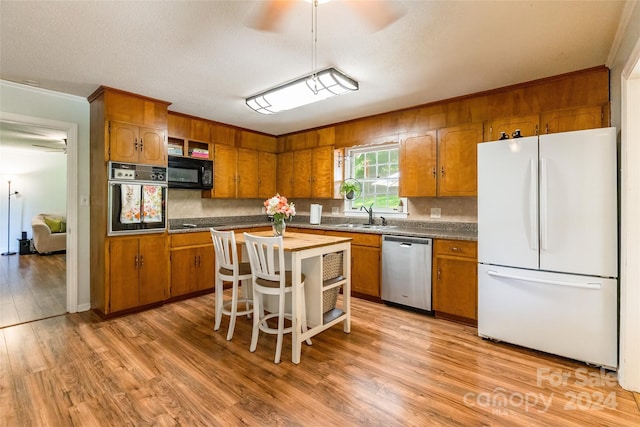 kitchen featuring stainless steel dishwasher, oven, a kitchen island, white fridge, and hardwood / wood-style flooring