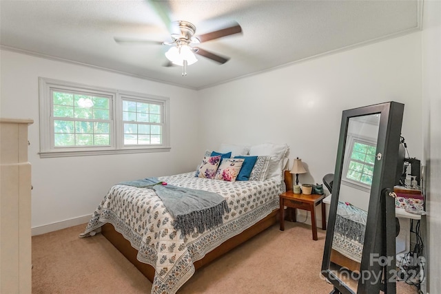 bedroom featuring ceiling fan, ornamental molding, and light colored carpet