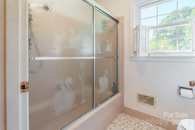 bathroom featuring tile patterned floors, bath / shower combo with glass door, and toilet