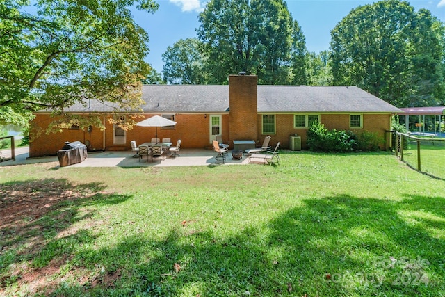 rear view of house featuring a trampoline, a patio area, and a lawn