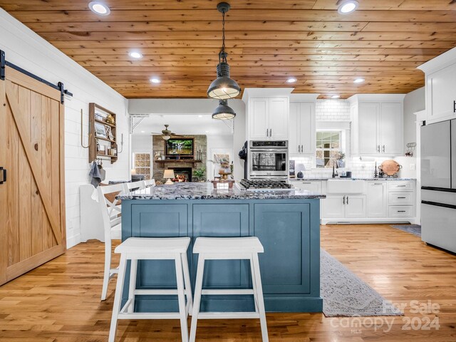 kitchen featuring light stone countertops, a barn door, white refrigerator, and white cabinets