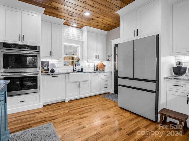 kitchen featuring light stone counters, stainless steel appliances, sink, white cabinets, and light hardwood / wood-style floors