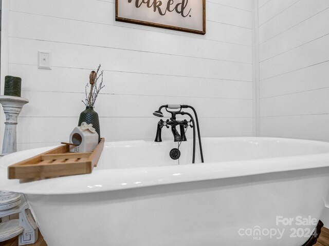 interior details with a tub and wood walls