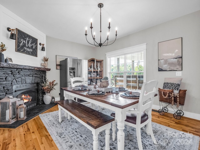 dining room with a notable chandelier, wood-type flooring, and a fireplace