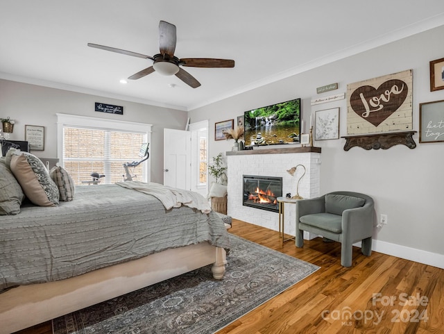 bedroom featuring ceiling fan, a fireplace, ornamental molding, and hardwood / wood-style flooring