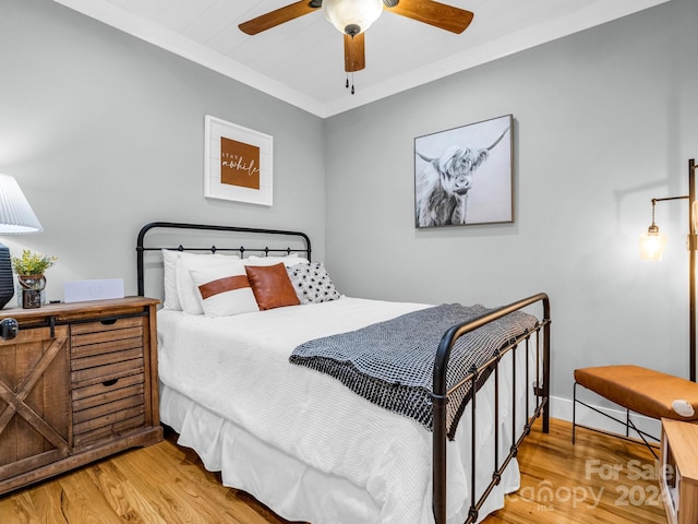 bedroom with hardwood / wood-style flooring, ceiling fan, and crown molding