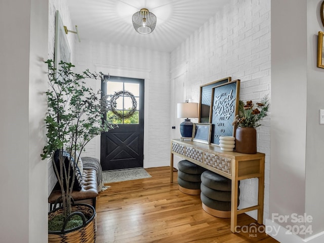 entrance foyer with hardwood / wood-style flooring and brick wall