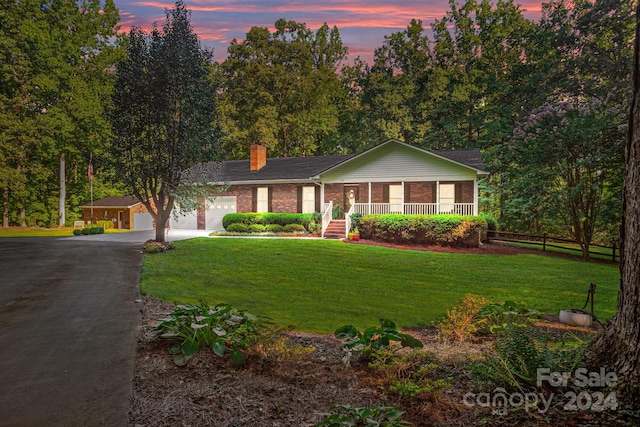 view of front of home with driveway, an attached garage, covered porch, a front lawn, and brick siding