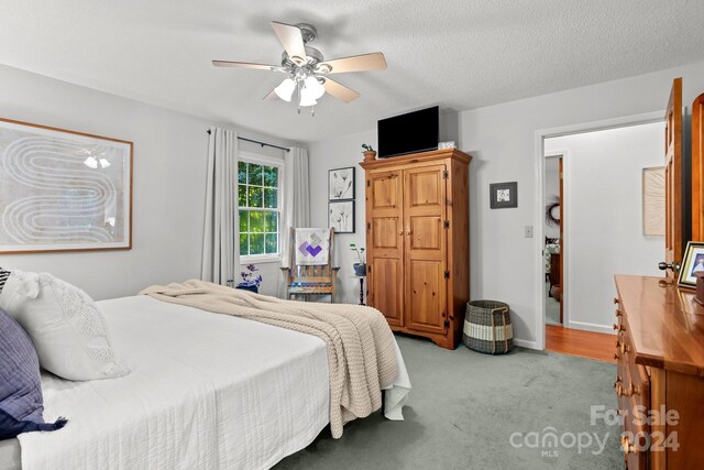 bedroom featuring ceiling fan, a textured ceiling, and light carpet