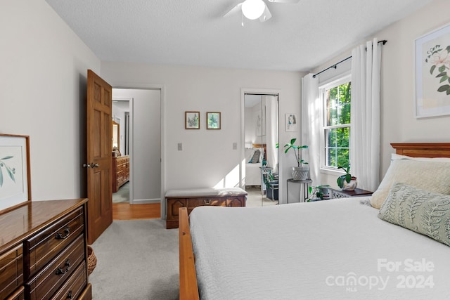 bedroom with a textured ceiling, ceiling fan, and light carpet