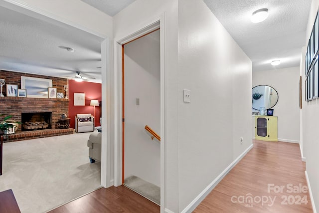 hall with light colored carpet and a textured ceiling