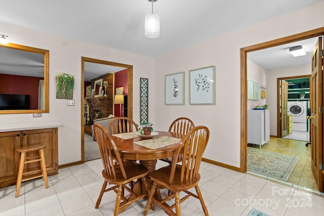 tiled dining room with a fireplace, brick wall, a textured ceiling, and washer / clothes dryer