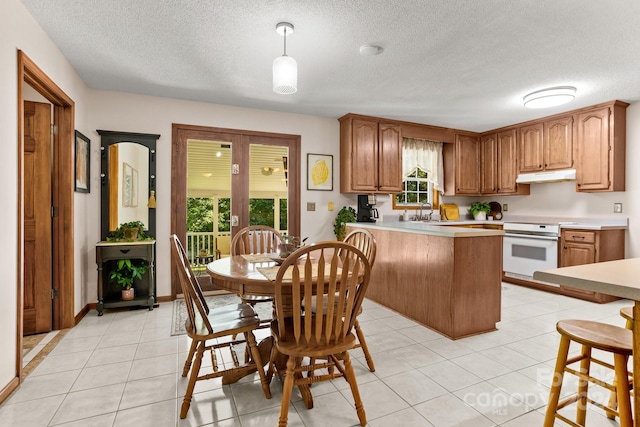 kitchen with hanging light fixtures, range, light tile patterned floors, sink, and kitchen peninsula