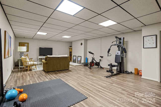 workout room featuring light wood-type flooring and a paneled ceiling