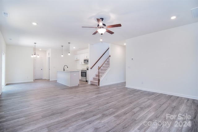 unfurnished living room with ceiling fan, light hardwood / wood-style flooring, and sink