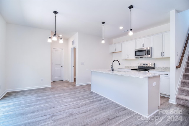 kitchen featuring light hardwood / wood-style flooring, white cabinets, appliances with stainless steel finishes, decorative light fixtures, and a center island with sink