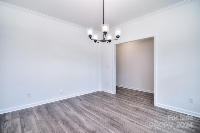 spare room with crown molding, wood-type flooring, and a chandelier