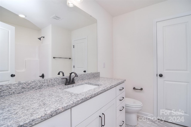 bathroom featuring toilet, a shower, and vanity