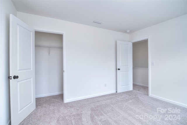 unfurnished bedroom with a closet and light colored carpet