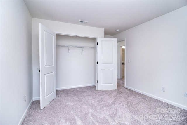 unfurnished bedroom with a closet and light carpet