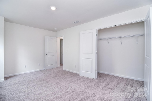 unfurnished bedroom featuring a closet and light carpet