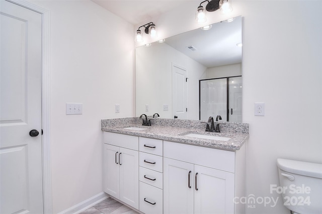 bathroom featuring tile patterned floors, toilet, vanity, and a shower with shower door