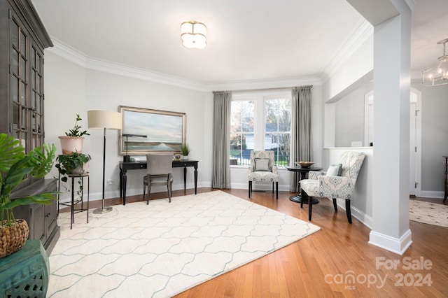 sitting room featuring hardwood / wood-style floors, crown molding, and an inviting chandelier