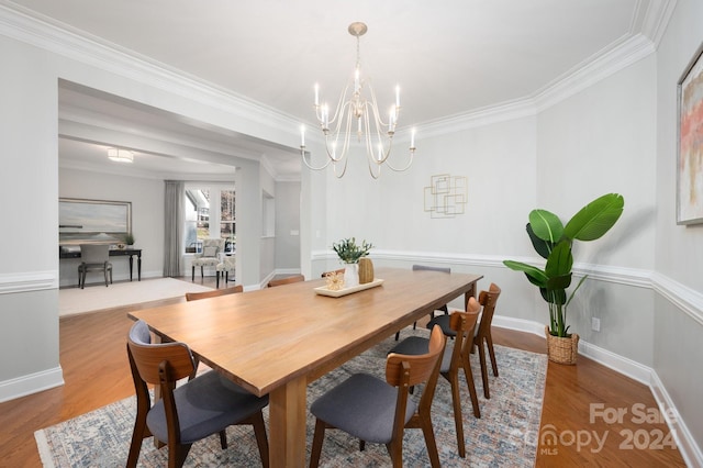 dining area featuring hardwood / wood-style floors, crown molding, and an inviting chandelier