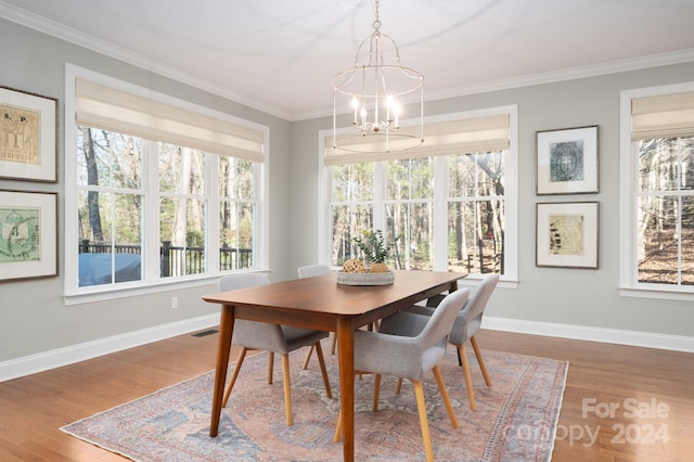 dining room featuring wood-type flooring, ornamental molding, and a notable chandelier