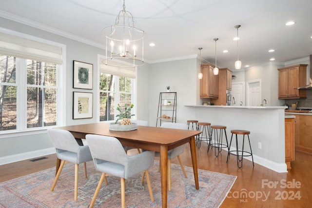 dining room with ornamental molding, light hardwood / wood-style flooring, a healthy amount of sunlight, and an inviting chandelier