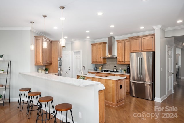 kitchen featuring kitchen peninsula, stainless steel appliances, dark wood-type flooring, wall chimney range hood, and decorative light fixtures