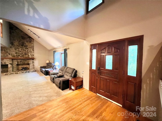 foyer with a healthy amount of sunlight, hardwood / wood-style floors, a fireplace, and vaulted ceiling