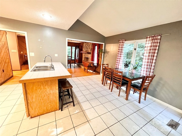 dining area featuring a wealth of natural light, vaulted ceiling, sink, and light hardwood / wood-style floors