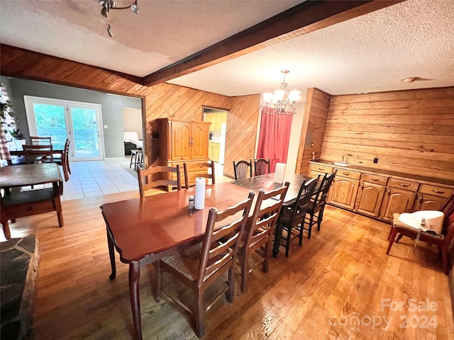 dining area with a textured ceiling, beamed ceiling, and light hardwood / wood-style floors