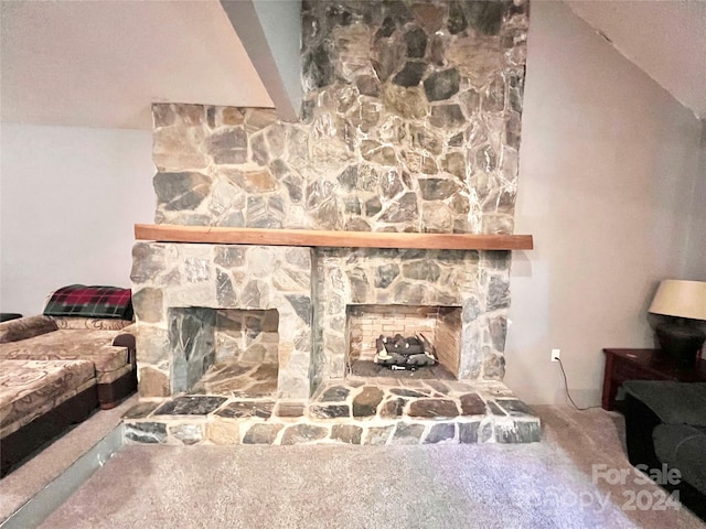 living room with lofted ceiling, carpet flooring, and a stone fireplace