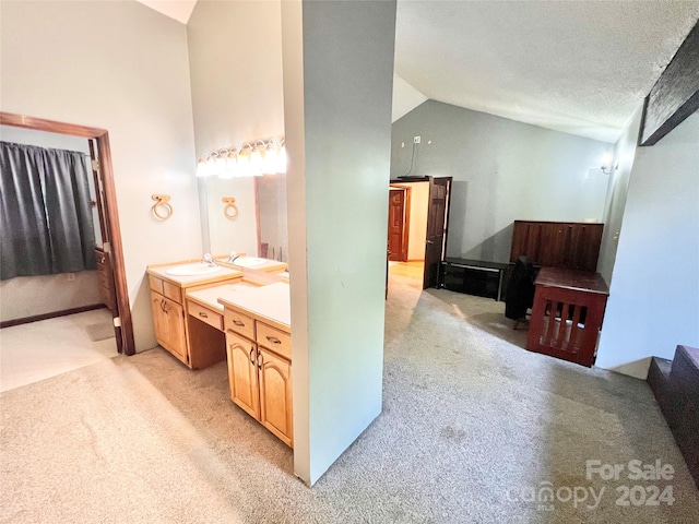 bathroom featuring a textured ceiling, vanity, and vaulted ceiling