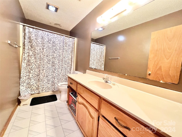 bathroom with tile patterned floors, toilet, a textured ceiling, and vanity