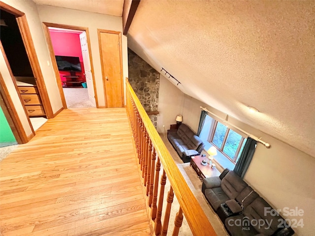 stairs with vaulted ceiling, a textured ceiling, and hardwood / wood-style floors