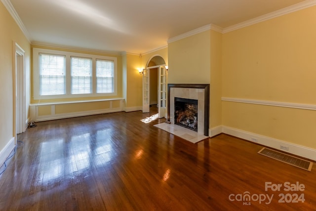 unfurnished living room with a tiled fireplace, ornamental molding, and wood-type flooring