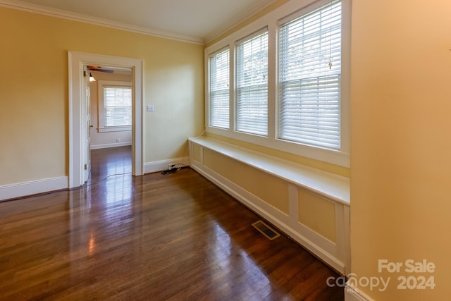 unfurnished room featuring crown molding, dark wood-type flooring, and a wealth of natural light