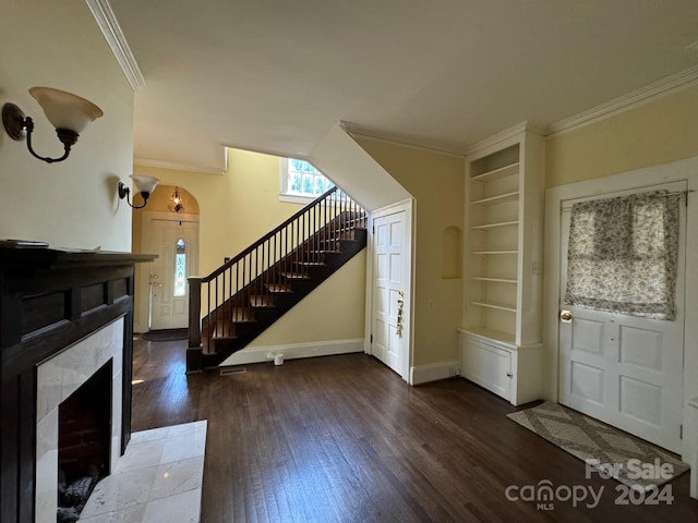 entrance foyer with hardwood / wood-style flooring, a tiled fireplace, and crown molding