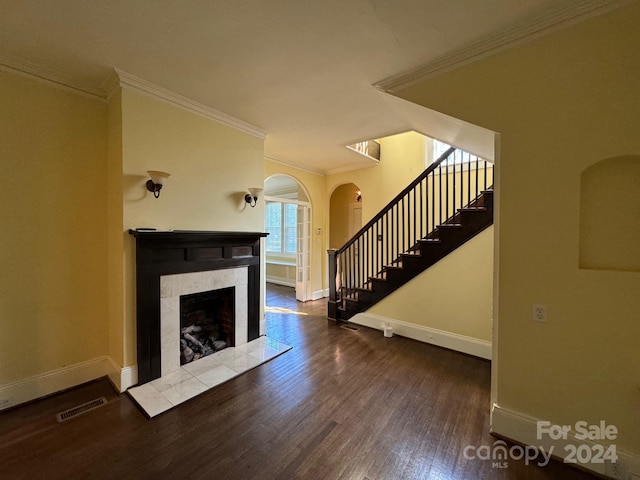 unfurnished living room featuring crown molding, a tiled fireplace, and hardwood / wood-style flooring