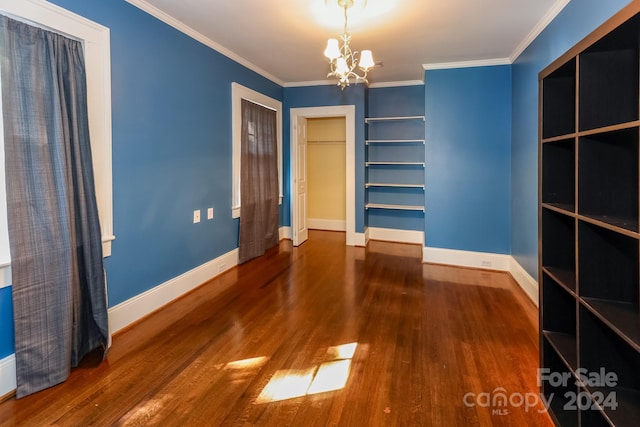 empty room with ornamental molding, wood-type flooring, and a notable chandelier