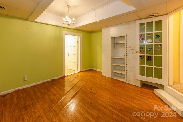 unfurnished room with a raised ceiling, hardwood / wood-style floors, and a notable chandelier